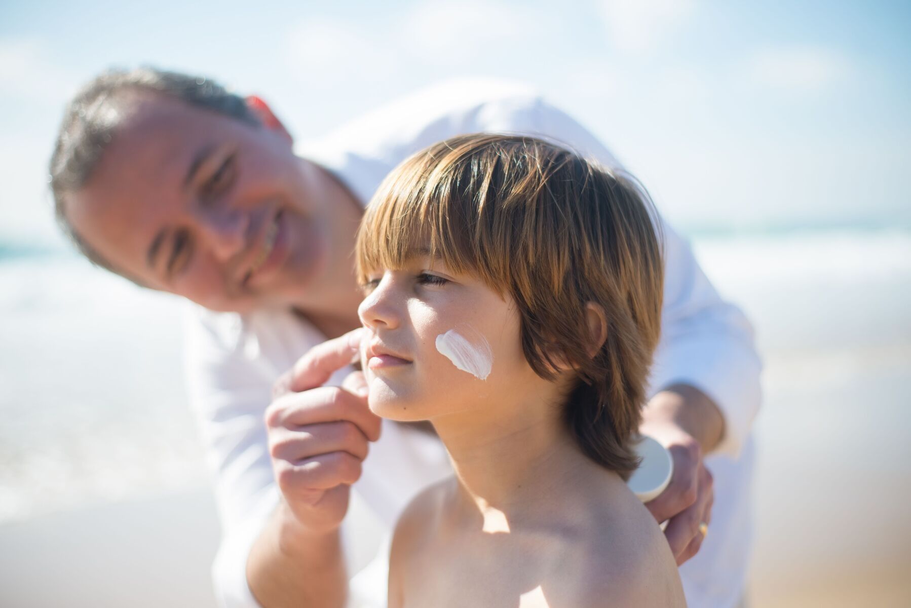 Father applying sunscreen to son